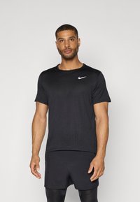 Black athletic T-shirt with a round neck and short sleeves. Features subtle textured pattern and a white Nike logo on the chest.