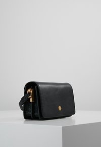 Černá kožená kabelka se strukturovaným tvarem, s akcentem zlatého kovu a texturovanou boční panelem. Kompaktní design ideální pro nezbytnosti.