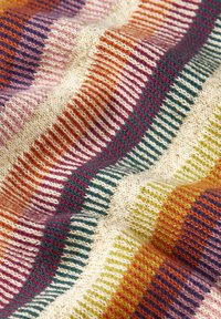 Texturiertes Strickgewebe mit wellenförmigen Streifen in Orange, Lila, Creme, Grün und Blaugrün, mit metallischen Akzenten im Gewebe.