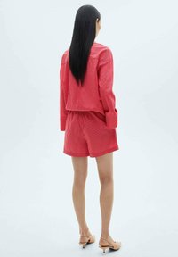 Ensemble de loungewear à rayures rouges comprenant une veste courte et un short. Fabriqué en tissu léger avec une texture lisse, conçu pour le confort.