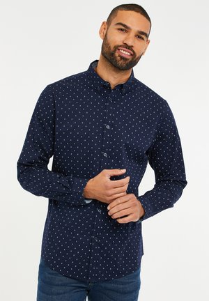Navyblaues Hemd mit Knöpfen, das ein kleines weißes Diamantmuster aufweist, lange Ärmel und einen Kragen hat. Hergestellt aus glattem Stoff mit einer körperbetonten Passform.