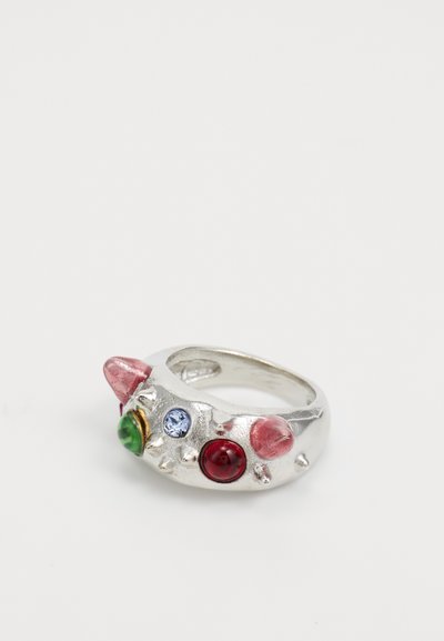 Silver ring featuring colorful gemstones: red, green, pink, and blue. Textured band with protruding accents. Circular shape.