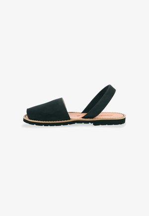 Sandales slingback en suède noir avec un profil bas, un embout rond et une semelle en caoutchouc. Le design minimaliste présente une texture lisse et une silhouette simple.