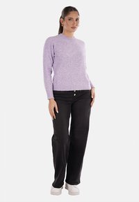 Maglione lilla in un morbido tessuto a maglia con scollatura a girocollo, abbinato a jeans neri a gamba larga e sneakers bianche. Tessuto morbido e forma aderente.