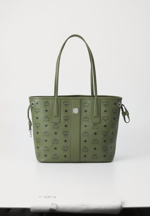 Sac fourre-tout en cuir vert avec double poignées, orné de logos noirs et de motifs en forme de diamant, présentant une plaque de marque en métal au centre.