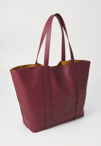 Maroon tote bag with smooth faux leather, two long handles, and a contrasting yellow interior. Features vertical seams for structure.