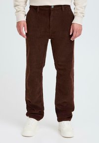 Brown corduroy trousers with a soft texture, straight leg design, front button closure, and side pockets, paired with white sneakers.