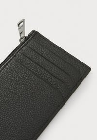 Black leather wallet with a textured surface, featuring a zip closure and four card slots on one side. Silver hardware accents visible.