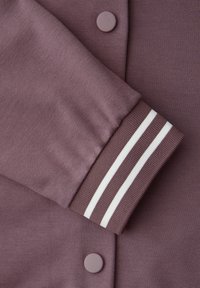 Manica di giacca in maglia malva con doppie strisce bianche sul polsino, tessuto malva sovrapposto con bottoni automatici malva abbinati.