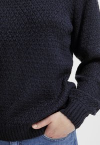 Navyblauer, strukturierten Strickpullover mit gerippten Bündchen und Saum. Verfügt über ein geometrisches Muster, weichen Stoff und eine lockere Passform.