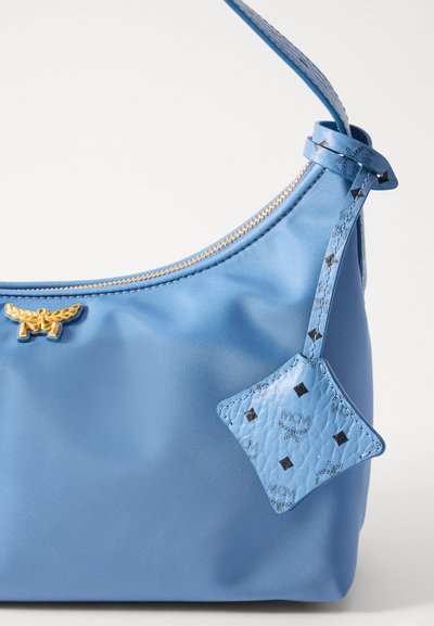 Blue synthetic handbag with gold hardware, a zip closure, and a detachable blue leather charm featuring a diamond pattern. Smooth texture.