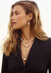 Kihilised pärli- ja hõbeehteketid, millel on suur pärliaktsent ja peened hõbeosad. Kanda musta bleiseri peal.