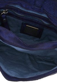 Borsa in suede blu con una tasca con zip, dotata di una morbida fodera interna. Include un'etichetta con dettagli e accenti di cucitura lungo i bordi.