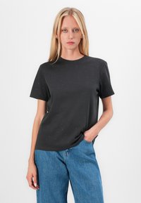 Black short-sleeve t-shirt with a round neck and subtle dot pattern, made of soft fabric. Paired with high-waisted blue denim jeans.