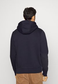 Marineblauer Hoodie mit verstellbarem Kordelzug für die Kapuze, weichem Stoff, gerippten Bündchen und einer lässigen Passform. Keine sichtbaren Details an der Vorderseite.