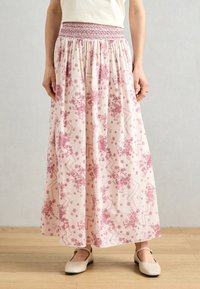 Floral printed maxi skirt with a smocked waist in light pink, featuring a mix of rose patterns and abstract shapes. Lightweight fabric.