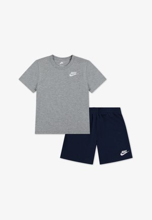 Hall hallist puuvillast lühikeste varrukatega T-särk valge Nike logoga, mida kannavad tumesinised lühikesed püksid elastsest vöökohast ja valge logoga.