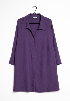 Fioletowa teksturowana sukienka koszulowa z długim rękawem, kołnierzykiem i guzikami z przodu, wisząca na czarnym wieszaku na białym tle.