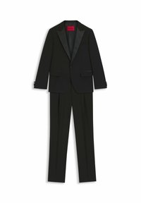 Completo smoking nero con giacca a rever in satin e pantaloni con parte frontale liscia, realizzato in tessuto morbido con una vestibilità strutturata. Etichetta interna rossa visibile.
