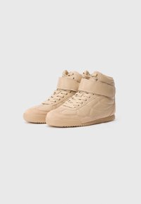 Baskets montantes beiges en cuir et suède, avec une cheville rembourrée, un laçage à l'avant et une sangle en velcro au milieu du pied.
