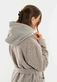 Vrouw met bruin haar dat naar achteren is gekleed, draagt een textuur grijs jasje met een brede geribde capuchon, vanuit de achterkant en zijkant getoond, tegen een witte achtergrond.