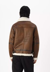 Giubbotto bomber in pelle marrone con colletto in pelliccia sintetica bianca, dotato di dettagli in pelle nera e cinturini regolabili all'orlo.