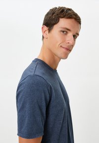 Mörkblå t-shirt med rund halsringning, tillverkad av mjukt och strukturerat tyg, med korta ärmar och en figursydd silhuett.