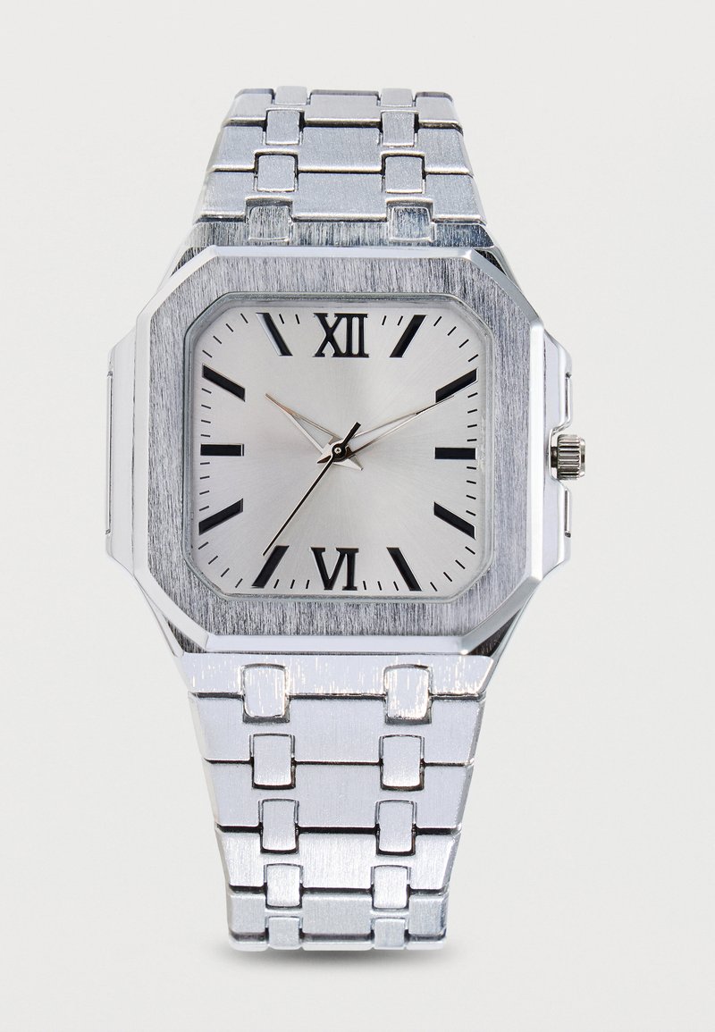 Montre-bracelet carrée en argent avec chiffres romains, index noirs et bracelet métallique relié, affichant 10:36:37.