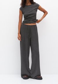Grå ribbad stickad kort topp med kapade ärmar och elastisk midja samt vida byxor. Texturerad tyg, avslappnad passform, matchande färgschema.