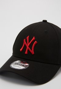 Boné de basebol preto com um logótipo "NY" em vermelho bordado na frente, com uma faixa ajustável e uma pala texturizada.