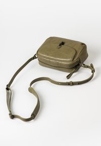Borsa a tracolla verde in pelle con forma rettangolare, chiusura a zip, tasca frontale piatta e tracolla regolabile. Texture liscia e hardware minimale.