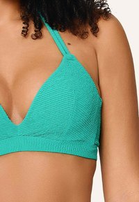 Tyrkysový trojuholníkový bikiny top s textúrovanou tkaninou, s tenkými nastaviteľnými popruhmi a nízkym V-výstrihom. Žiadne viditeľné detaily hardvéru.