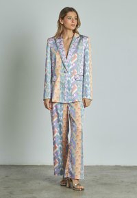 Traje multicolor con estampado, que presenta diseños geométricos en tonos pastel, con un escote profundo, dos bolsillos frontales y cierre de un botón.