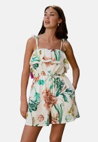 Bloemen jumpsuit met een gerimpelde halslijn, verstelbare bandjes en een elastische taille. Kleuren zijn onder andere pastelroze, groen en geel op een lichte achtergrond.