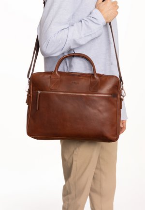 Rjava usnjena torba z dvema zgornjima ročajema in snemljivim trakom. Ima sprednji žep z zadrgo in mehko, gladko teksturo.