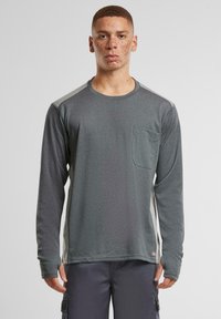 Langermet grå skjorte med lomme, med teksturert stoff og lysegrå sidestykker. Crew neck-design med lett tettsittende ermer.