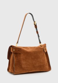Borsa in suede marrone con forma strutturata, manici in pelle nera, dettagli in metallo dorato e tasche laterali rettangolari.