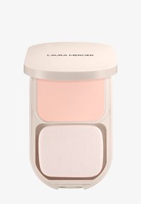 Polvo compacto con un estuche beige y redondeado. Presenta un polvo rosa claro y un aplicador suave y blanco en la parte inferior. Nombre de la marca en la parte superior.