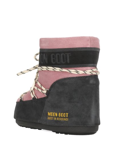 Botte de neige à coupe haute avec tige rose, partie inférieure noire rembourrée, lacets blancs, et étiquette jaune "MOON BOOT Guest in Residence" sur le côté.