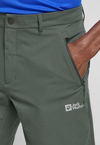 Pantalons d'extérieur verts au design épuré, dotés d'une poche zippée et d'accents de logo. Fabriqués à partir d'un matériau léger et flexible.