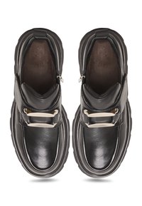 Zapatos de cuero negro con textura suave, presentan dos cremalleras laterales, una correa ancha con detalle de hebilla y una suela gruesa.