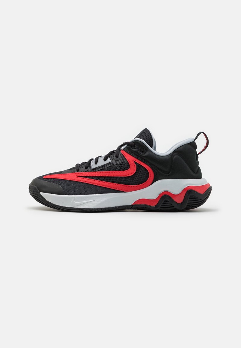 Baskets de sport noires, rouges et blanches avec une tige en mesh noir, un design swoosh rouge, une semelle intermédiaire blanche et une semelle extérieure ondulée noire et rouge.
