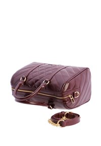 Bolso de mano de cuero acolchado burdeos con cremallera dorada y correa desmontable, mostrado sobre fondo blanco.