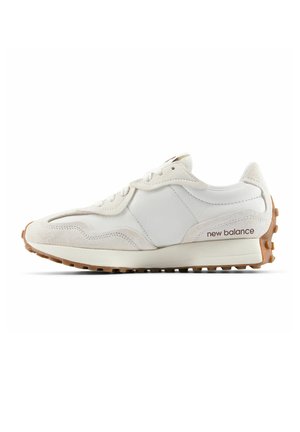 Baskets New Balance blanches et beiges avec des superpositions en daim, un laçage à l'avant et une semelle en caoutchouc texturé marron avec un grip au talon.