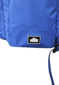Mochila azul hecha de un tejido duradero con una textura suave. Presenta un logo de nube en un parche rectangular negro y una correa lateral.