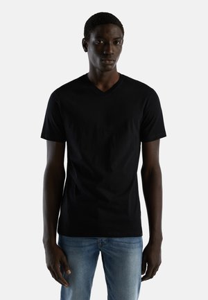 Zwarte V-hals t-shirt gemaakt van zachte katoen, heeft korte mouwen en een klassieke pasvorm, gedragen met lichtblauwe jeans.