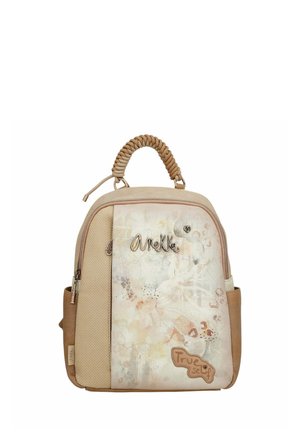 Sac à dos beige avec une façade texturée, arborant des motifs floraux et le texte "Véritable soi." Comprend une poignée tissée en haut et des compartiments zippés.