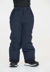 Pantalons de neige bleu marine en matériau imperméable avec taille ajustable, poches et poignets élastiques. Chaussures noires visibles en bas.
