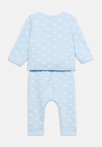 Φωτογραφία παιδικής πιτζάμας σε ανοιχτό μπλε χρώμα με μακριά μανίκια και παντελόνι, διακοσμημένη με λευκό μοτίβο φάλαινας σε όλο το ύφασμα.