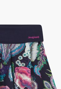 Flerfärgade blommiga kjol med en marinblå midja som har rosa "Desigual"-logga. Tyget har en slät textur och ett livligt mönster.